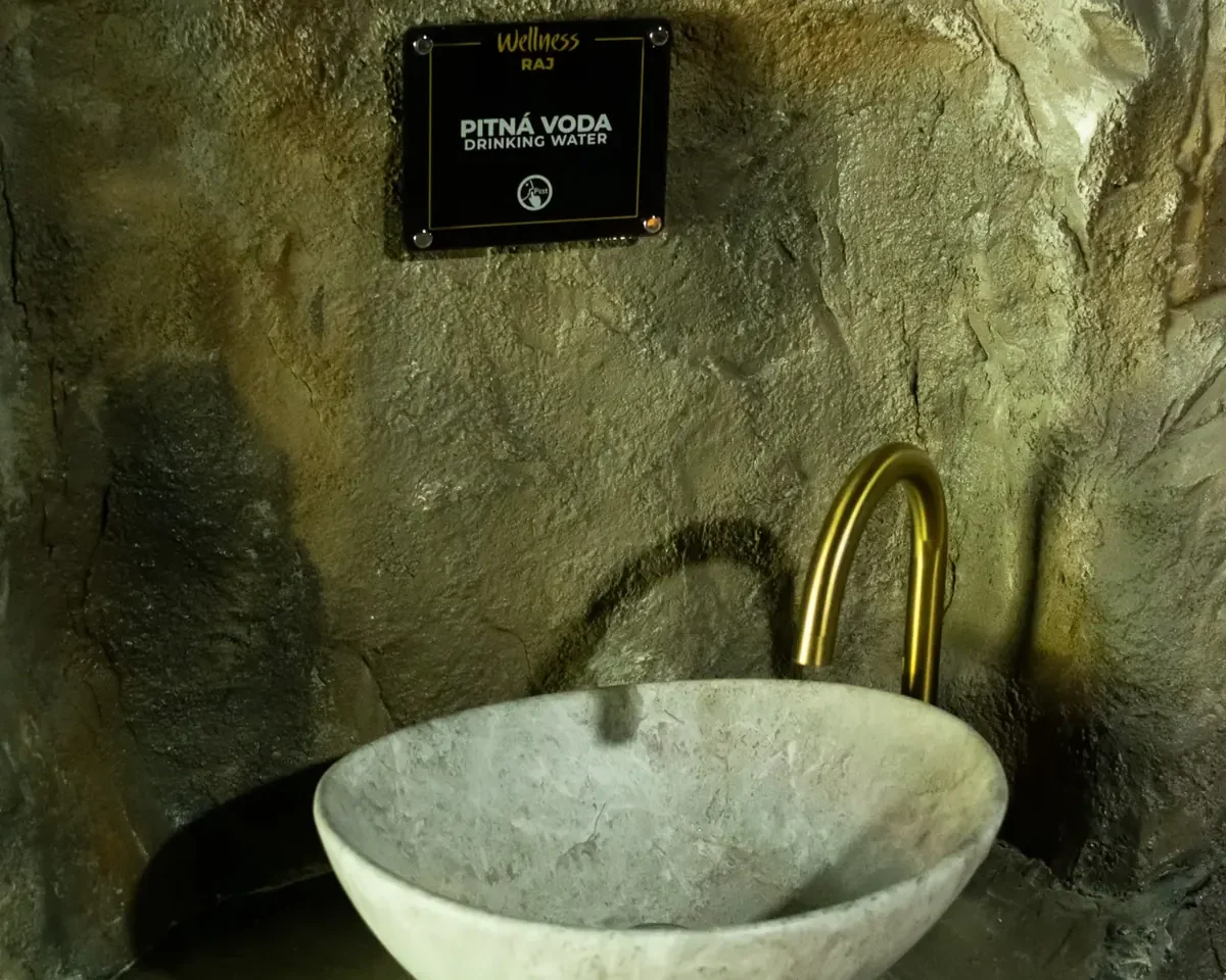 Kamenné umyvadlo osazené ve skalní stěně wellness zóny