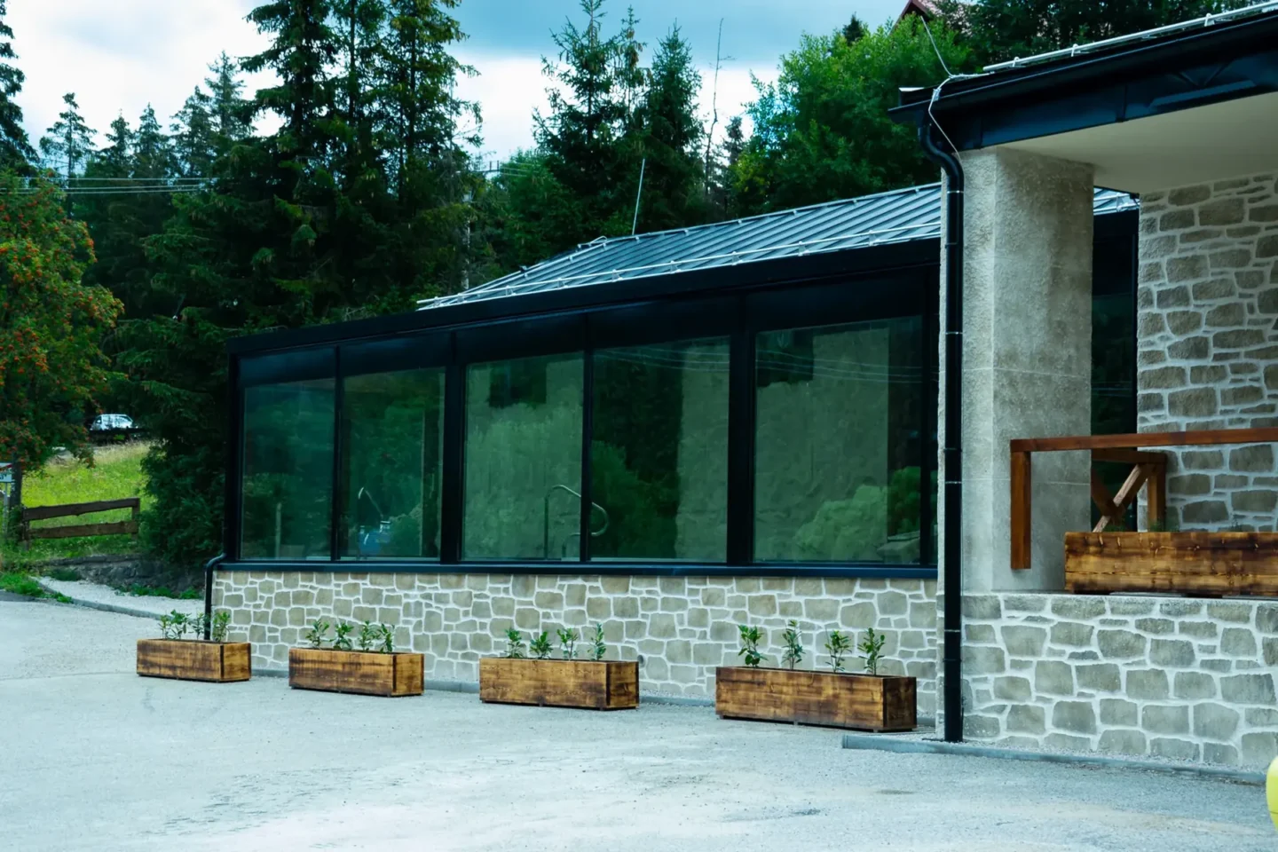 Prosklená budova wellness Hotelu Raj s dřevěným obkladem a květináči