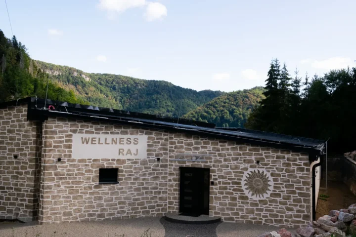 Budynek wellness Hotelu Raj z napisem Wellness Raj i widokiem na okoliczne wzgórza